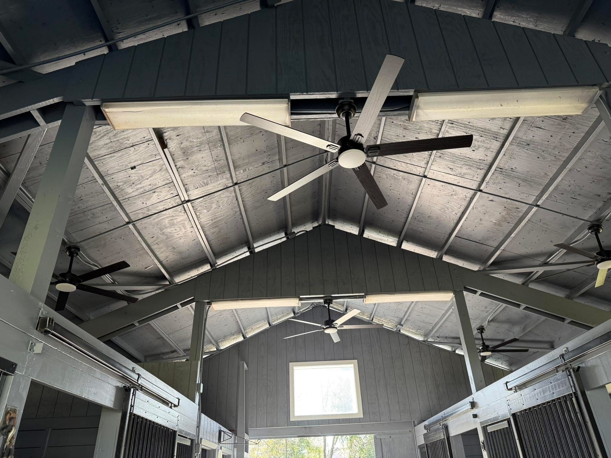A spacious barn-like interior with a high ceiling, multiple ceiling fans, and a skylight.