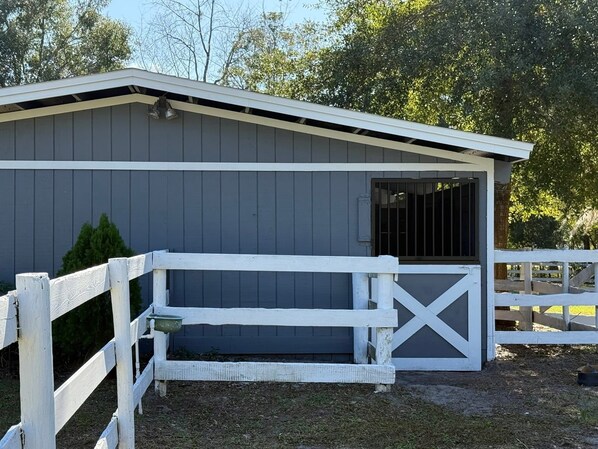 A stable with a white fence and a grey building.
