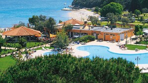 A resort with a swimming pool, beach, and mountainous backdrop. - Mobile Home in Rabac With Shared Pool (Labin)