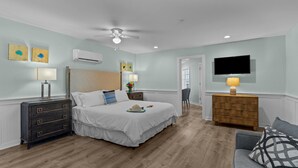 A bedroom with a bed, dresser, TV, and ceiling fan. - Loggerhead Inn & Suites - King Suite in hotel in Surf City, North Carolina (Surf City)