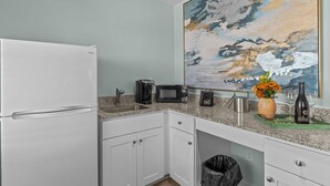 A compact kitchen with a refrigerator, microwave, coffee maker, and a small sink. - Loggerhead Inn & Suites - King Suite in hotel in Surf City, North Carolina (Surf City)