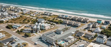 Luchtbeeld van een kustgebied met woningen, een strand en een parkeerplaats.