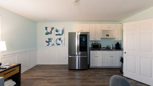 A modern kitchen with white cabinets, a stainless steel refrigerator, and a microwave. - Loggerhead Inn & Suites - King Premium Suite in hotel in Surf City, North Carolina (Surf City)