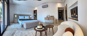 A modern hotel room with a bed, a sofa, a dining table, and a large mirror. -  villa bidouane luxury (marrakesh)