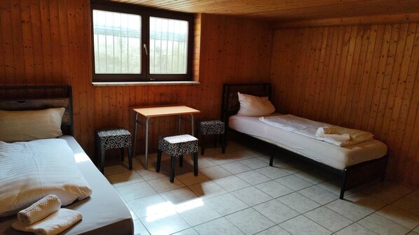 Ein Zimmer aus Holz mit zwei Betten, einem kleinen Tisch und zwei Hocker.