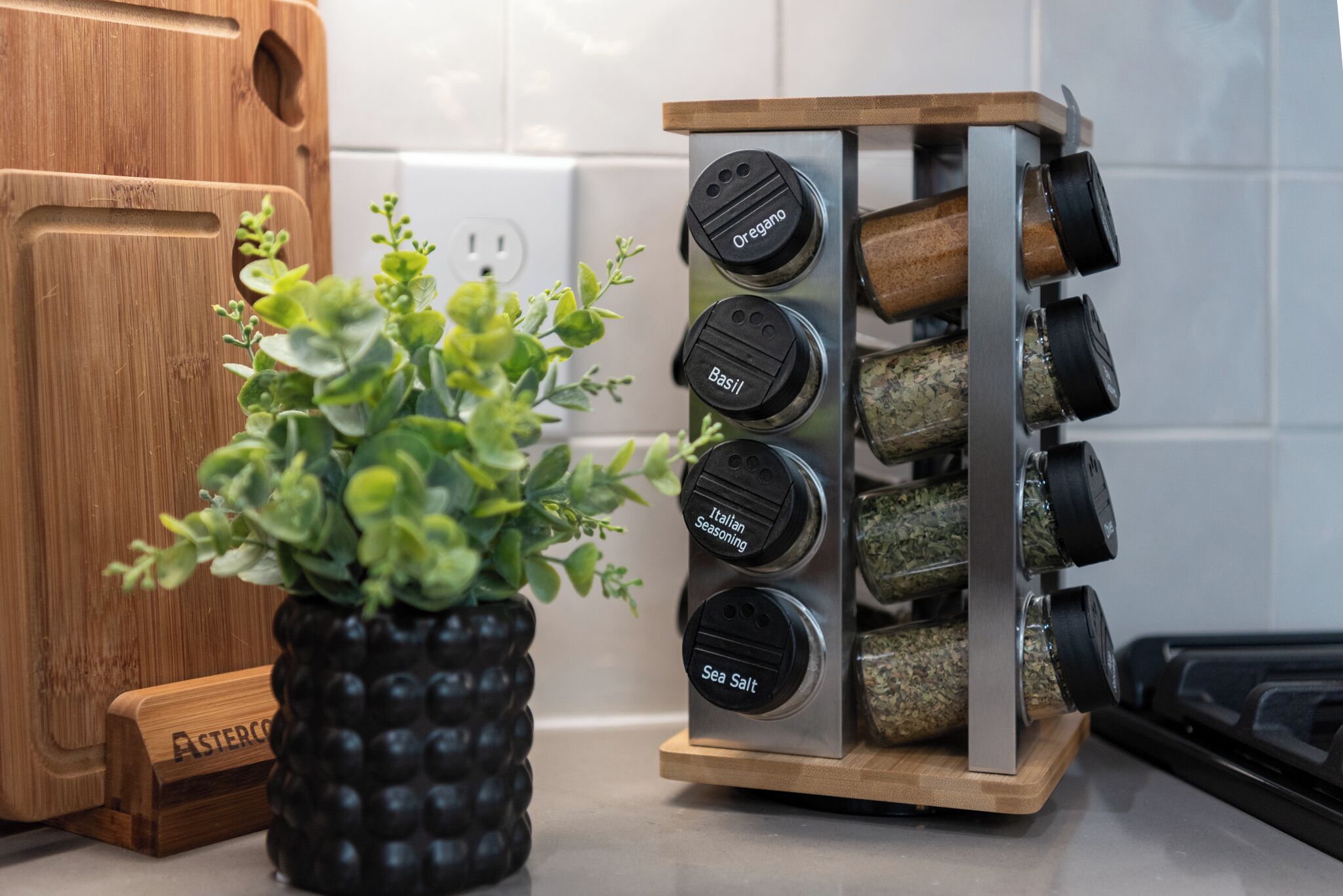 Een keuken met een houten snijplank, een potplant, een kruidenrek met gelabelde potjes en een messenblok.