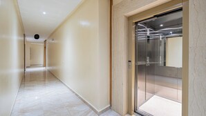Een gang met een marmeren vloer die leidt naar een lift.