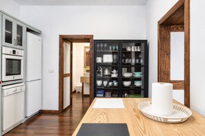 A kitchen with white appliances, a wooden table with a roll of paper towels, and a black cabinet with dishes. - GuestReady - Villa Private Pool (Santa Cruz de Tenerife)