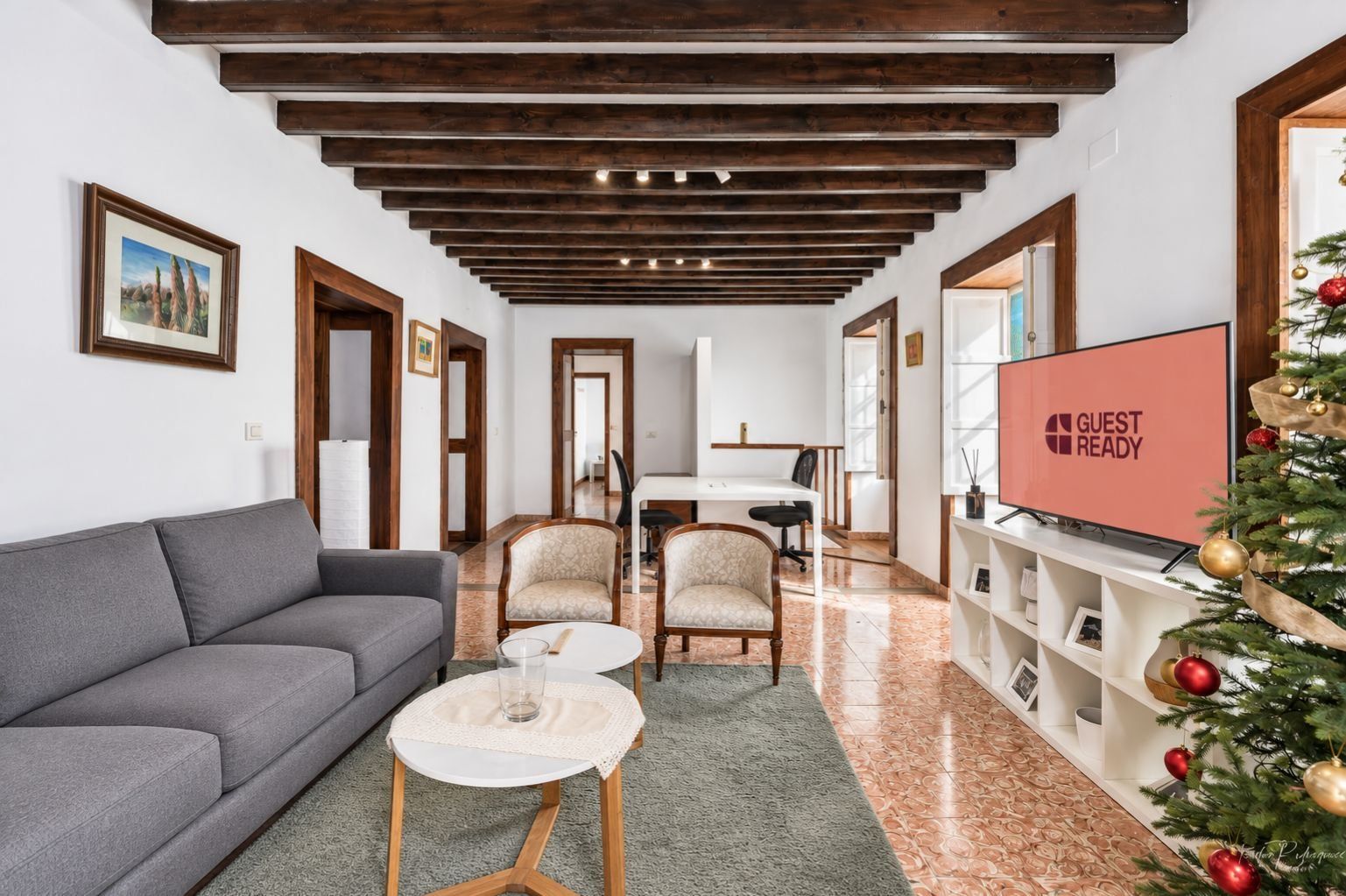 Una sala moderna con un sofá gris, dos sillones, una mesa de centro, un televisor y un árbol de Navidad.