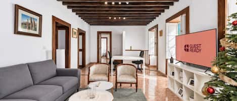 Una sala moderna con un sofá gris, dos sillones, una mesa de centro, un televisor y un árbol de Navidad.