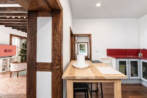 A modern kitchen with a wooden table, a red countertop, and a built-in sink. - GuestReady - Villa Private Pool (Santa Cruz de Tenerife)