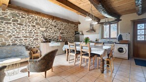 Una cocina rústica con paredes de piedra, muebles de madera y un comedor con mesa y sillas.