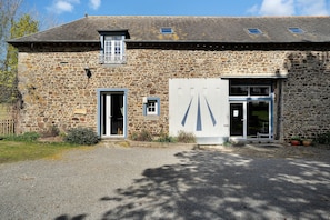 A stone building with a gravel driveway, a wooden door, and a small window.