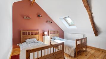 A bedroom with two wooden beds, a red accent wall, a skylight, and a small window.