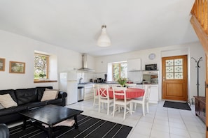 A modern kitchen with white cabinets, a black countertop, and a red tablecloth-covered dining table.