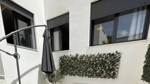 A patio with a white sofa, a small table, a chair, and a potted plant. - 2BR City Center Medina With Terrace Rabat (Rabat)