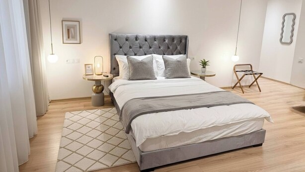 A modern bedroom with a large bed, a bedside table, a small round table, and a chair. - 2BR City Center Medina With Terrace Rabat (Rabat)