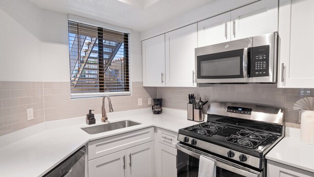 A modern kitchen with white cabinets, a stainless steel stove, a microwave, and a window with blinds. - Upscale Stay w Heated Pool 8mins to ASU (Tempe)
