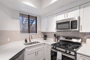 A modern kitchen with white cabinets, a stainless steel stove, a microwave, and a window with blinds. - Upscale Stay w Heated Pool 8mins to ASU (Tempe)