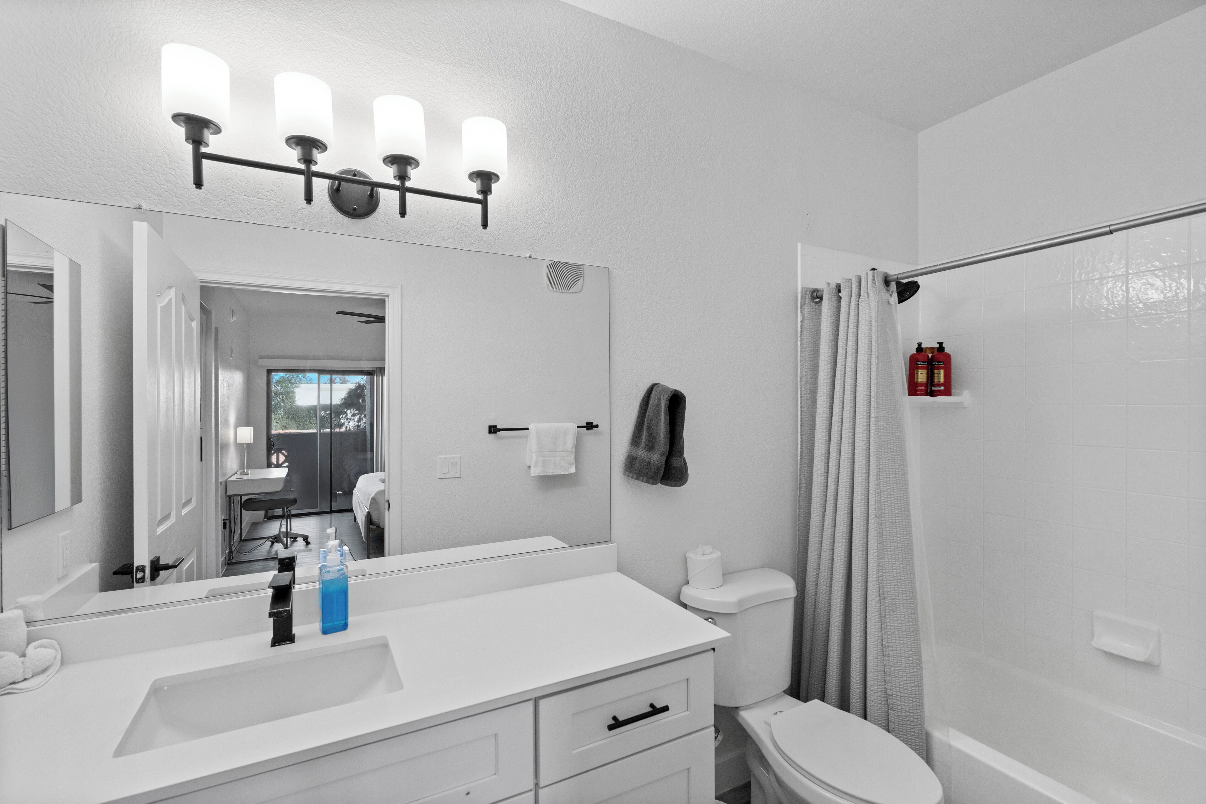 A bathroom with a white sink, a mirror, a towel rack, and a shower curtain.