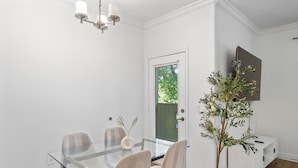 A modern dining area with a glass table, chairs, a potted plant, a white console, and a ceiling light fixture. - Upscale Stay w Heated Pool 8mins to ASU (Tempe)