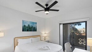A hotel room with a bed, a ceiling fan, a painting, a nightstand with a lamp, a table, and a chair. - Upscale Stay w Heated Pool 8mins to ASU (Tempe)