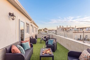 Terraço no telhado com mobiliário ao ar livre, uma mesa de jantar com comida e vista para a paisagem urbana.