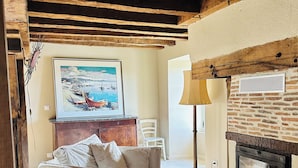 A cozy living room with a fireplace, a sofa, and a rug. - Gîte du Alchimiste on the Château de Dompierre estate (Dompierre-les-Églises)