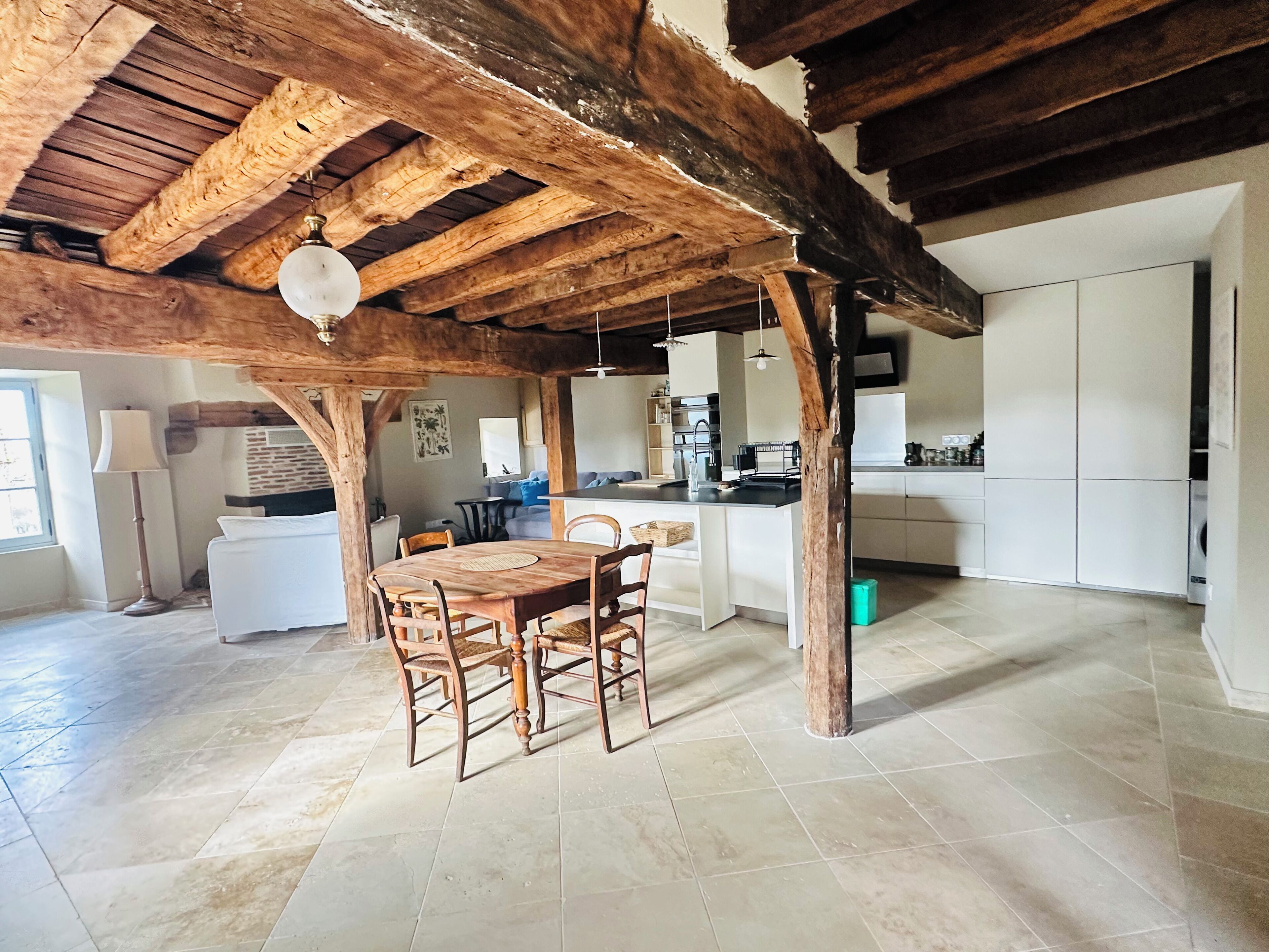 Una cocina amplia con comedor, vigas de madera y piso de baldosas.