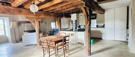 Una cocina amplia con comedor, vigas de madera y piso de baldosas.