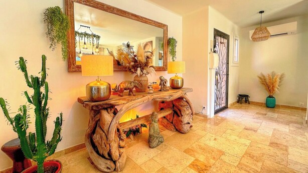 Um console de madeira com duas lâmpadas, um espelho e objetos decorativos.