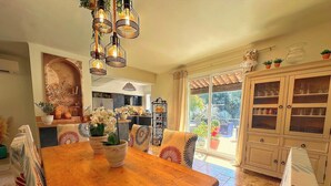 Uma sala de jantar espaçosa com uma mesa de madeira, cadeiras e um lustre.