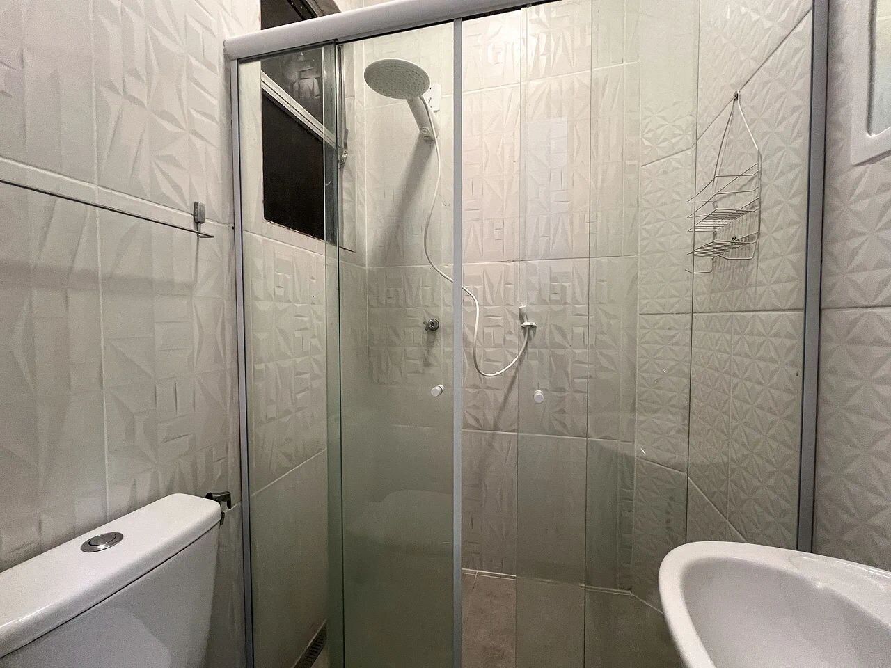 A bathroom with a glass-enclosed shower, a toilet, and a sink.