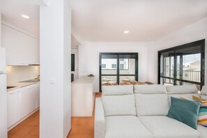 Eine moderne Wohnung mit Küche, Essbereich und Wohnzimmer mit Sofa sowie ein Balkon mit Blick.