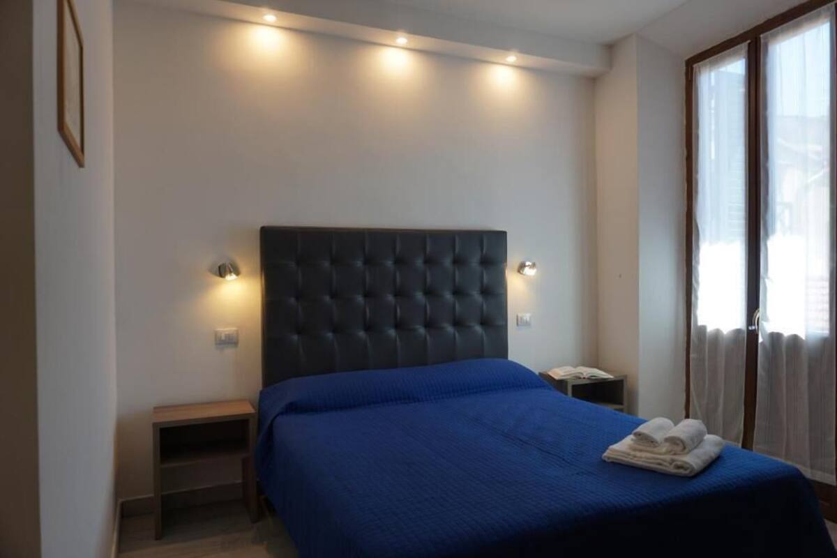 A bedroom with a large bed, bedside tables, and a window with curtains.