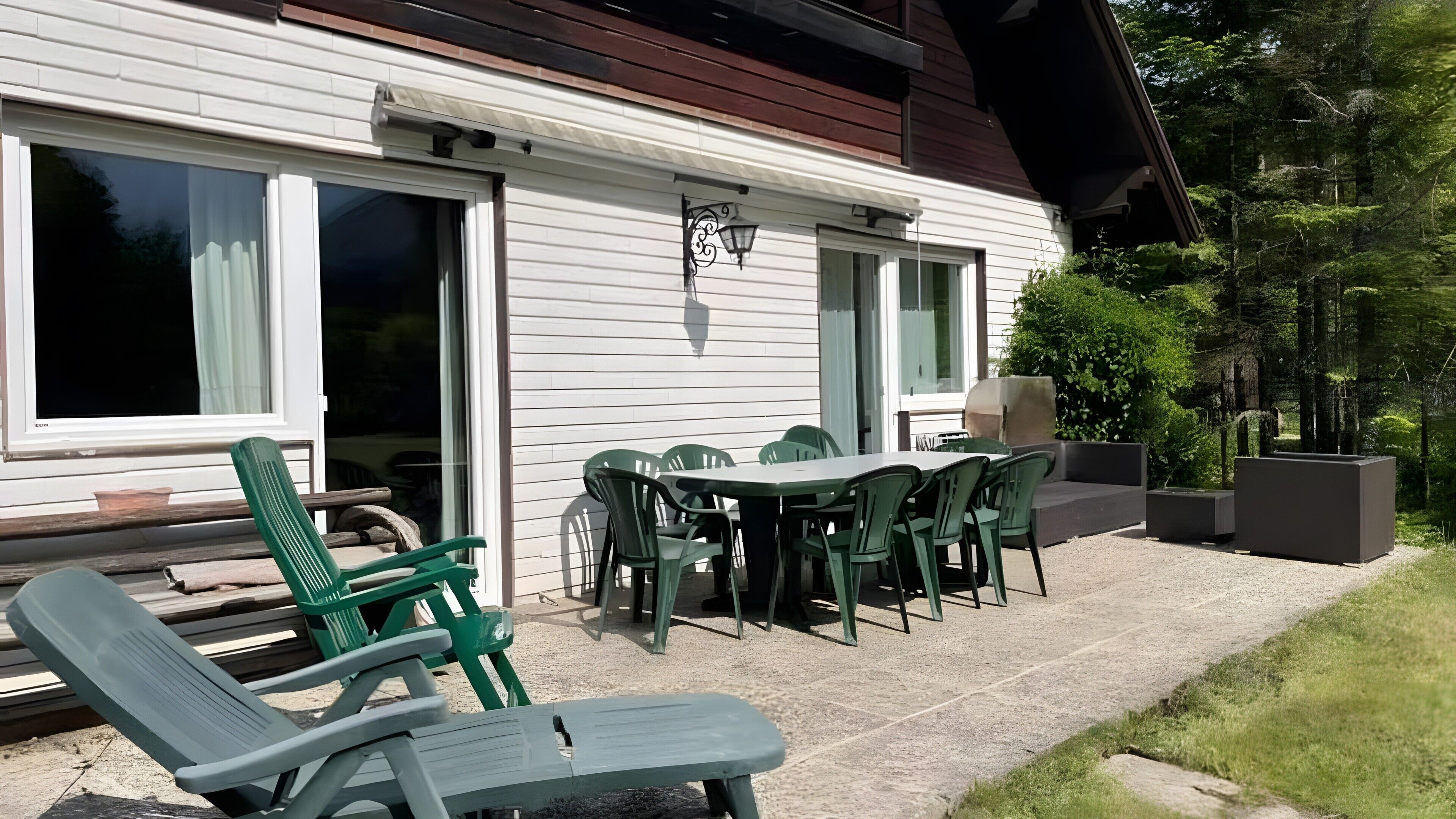 Een terras met tuinmeubilair, een tafel en stoelen.