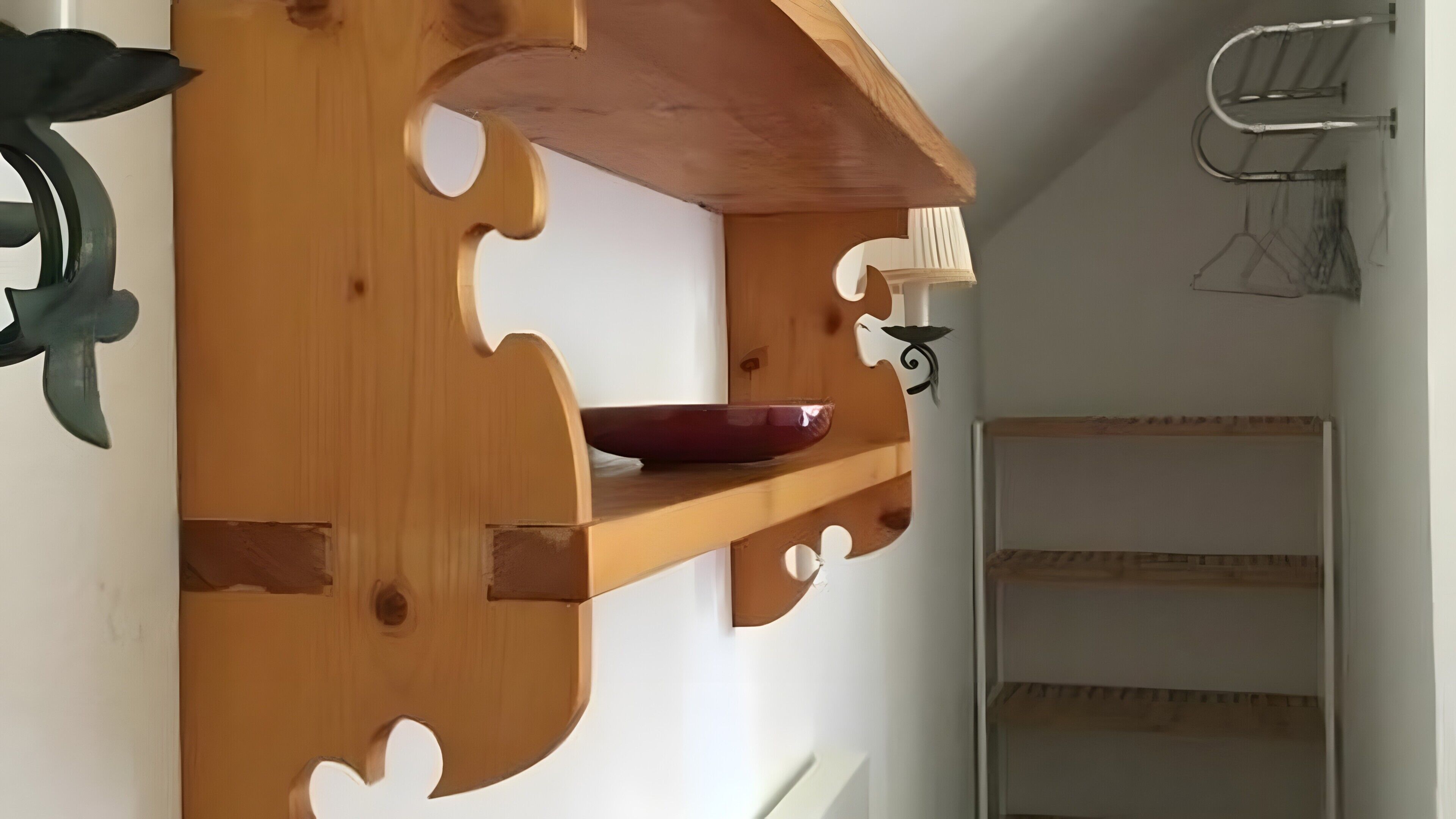 Ein Holzregal mit einer roten Schüssel, einem Metallgestell und einer weißen Wand.