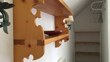 Ein Holzregal mit einer roten Schüssel, einem Metallgestell und einer weißen Wand.