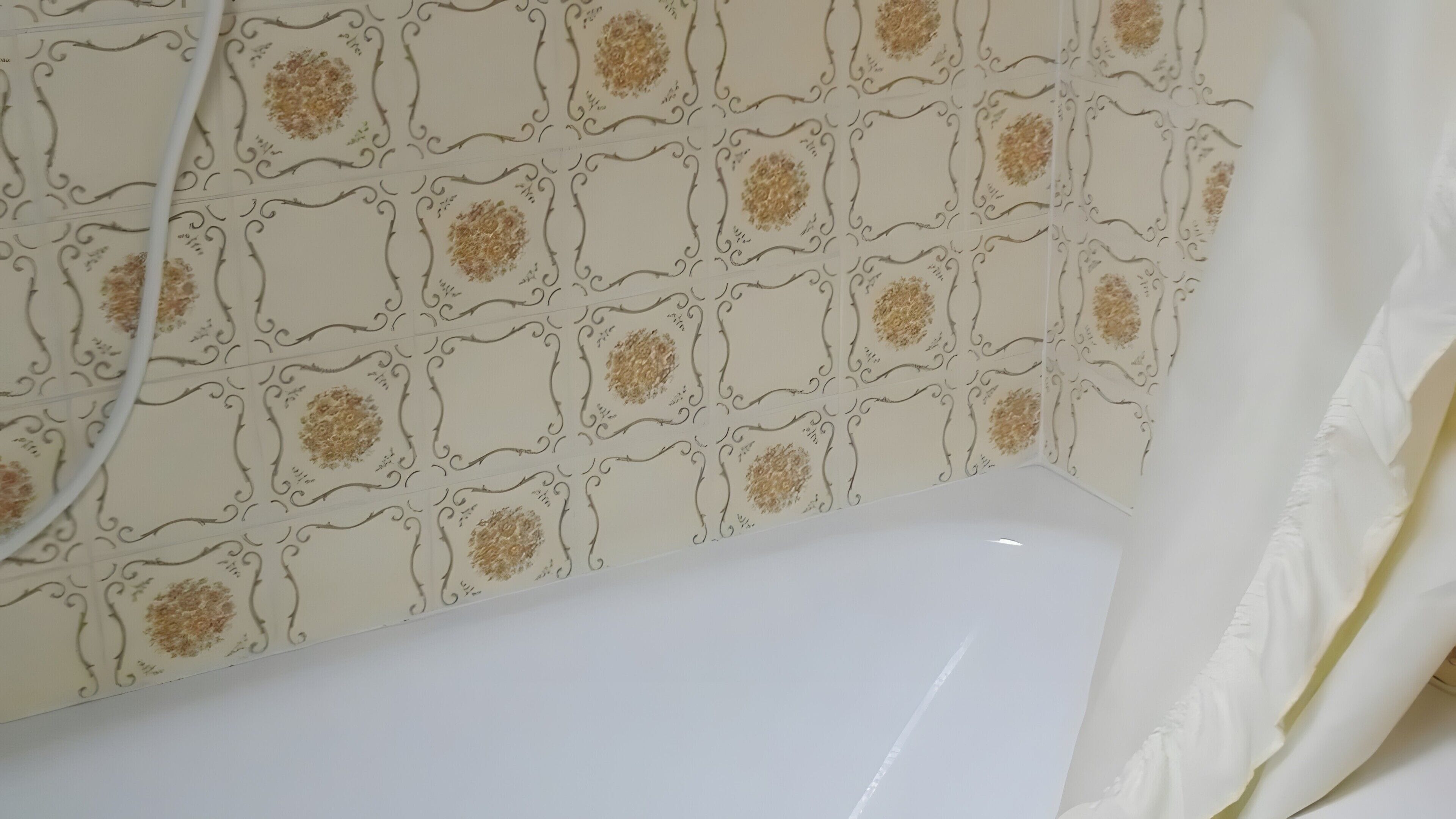 Une salle de bain avec un mur à motifs, une baignoire et un rideau de douche.