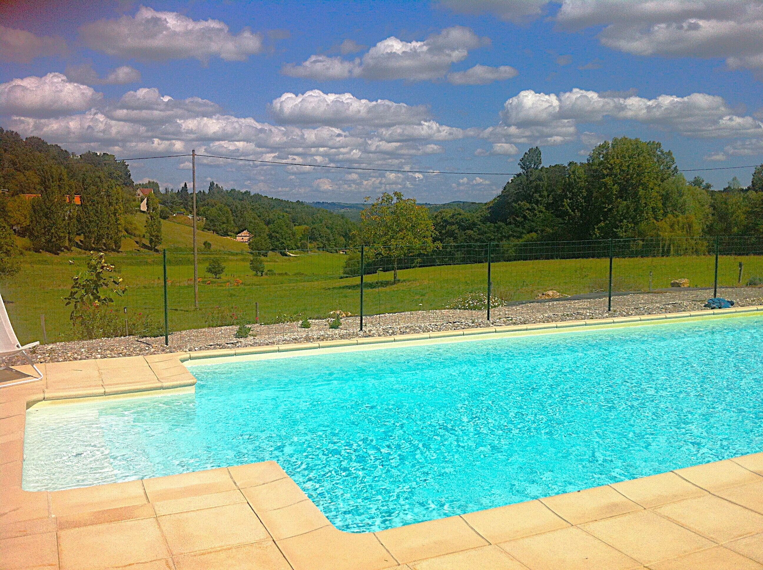 Ein Swimmingpool mit glasklarer, blauer Wasseroberfläche, umgeben von einer gepflasterten Liegefläche.