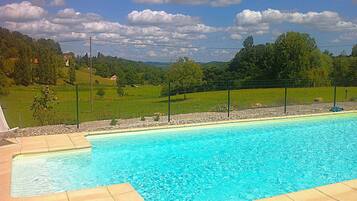 Ein Swimmingpool mit glasklarer, blauer Wasseroberfläche, umgeben von einer gepflasterten Liegefläche.