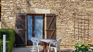 Un edificio de piedra con puerta de madera, una mesa con sillas y un pequeño jardín.