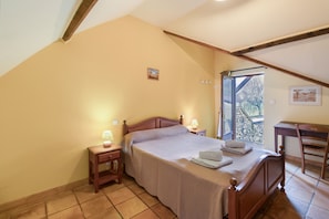 A bedroom with a bed, bedside tables, a chair, a window, and a picture on the wall.