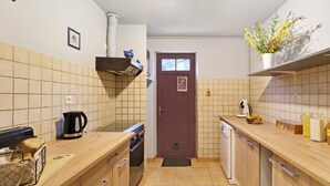 Una cocina compacta con encimera de madera, horno integrado, cafetera y un ventanal pequeño.