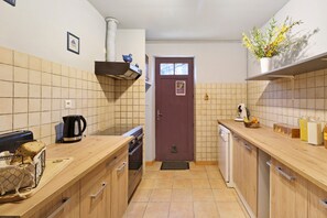 A compact kitchen with a wooden countertop, a built-in oven, a coffee maker, and a small window.