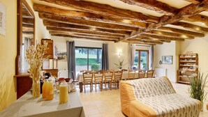 Una sala de estar con sofá, mesa de comedor, sillas, vigas de madera y una estantería.