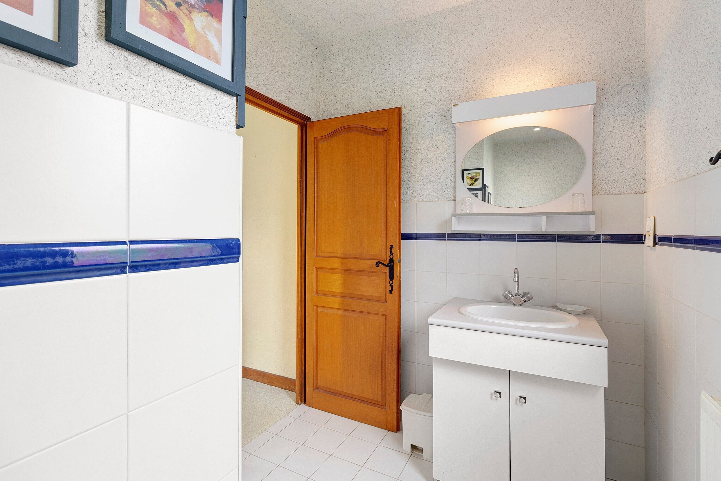 A bathroom with a wooden door, white sink, and blue-tiled walls.