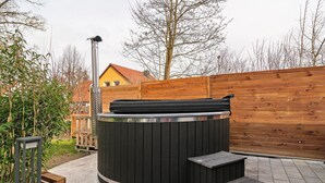 A hot tub with steps, a wooden fence, and a house in the background.