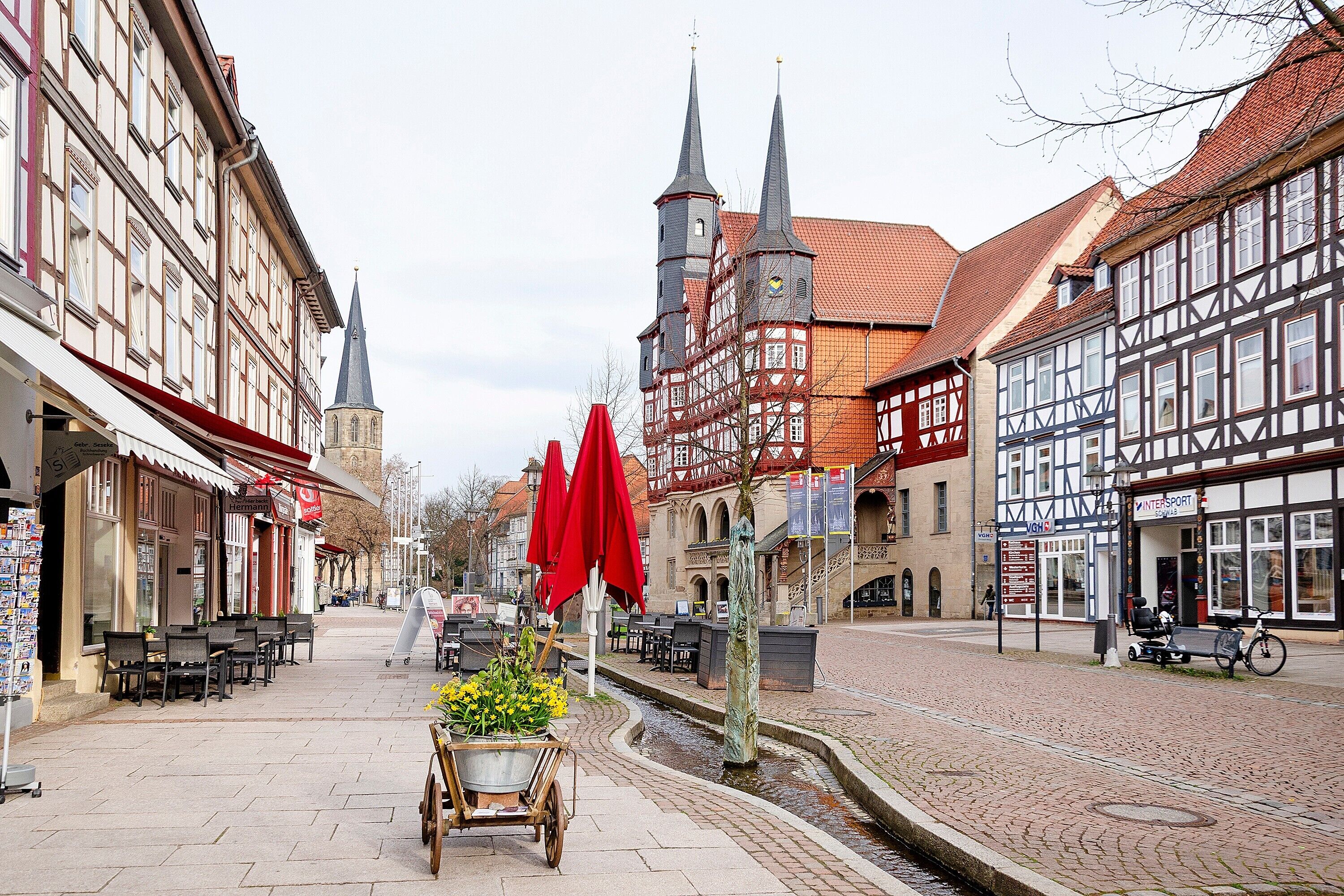Eine Kopfsteinpflasterstraße mit traditionellen Fachwerkhäusern, Außenbestuhlung und einem Kanal.