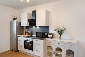 A modern kitchen with stainless steel appliances, white cabinetry, and a microwave on the countertop. - Holiday Home at Seeburgersee – Just 100 Meters from the Water (Seeburg)